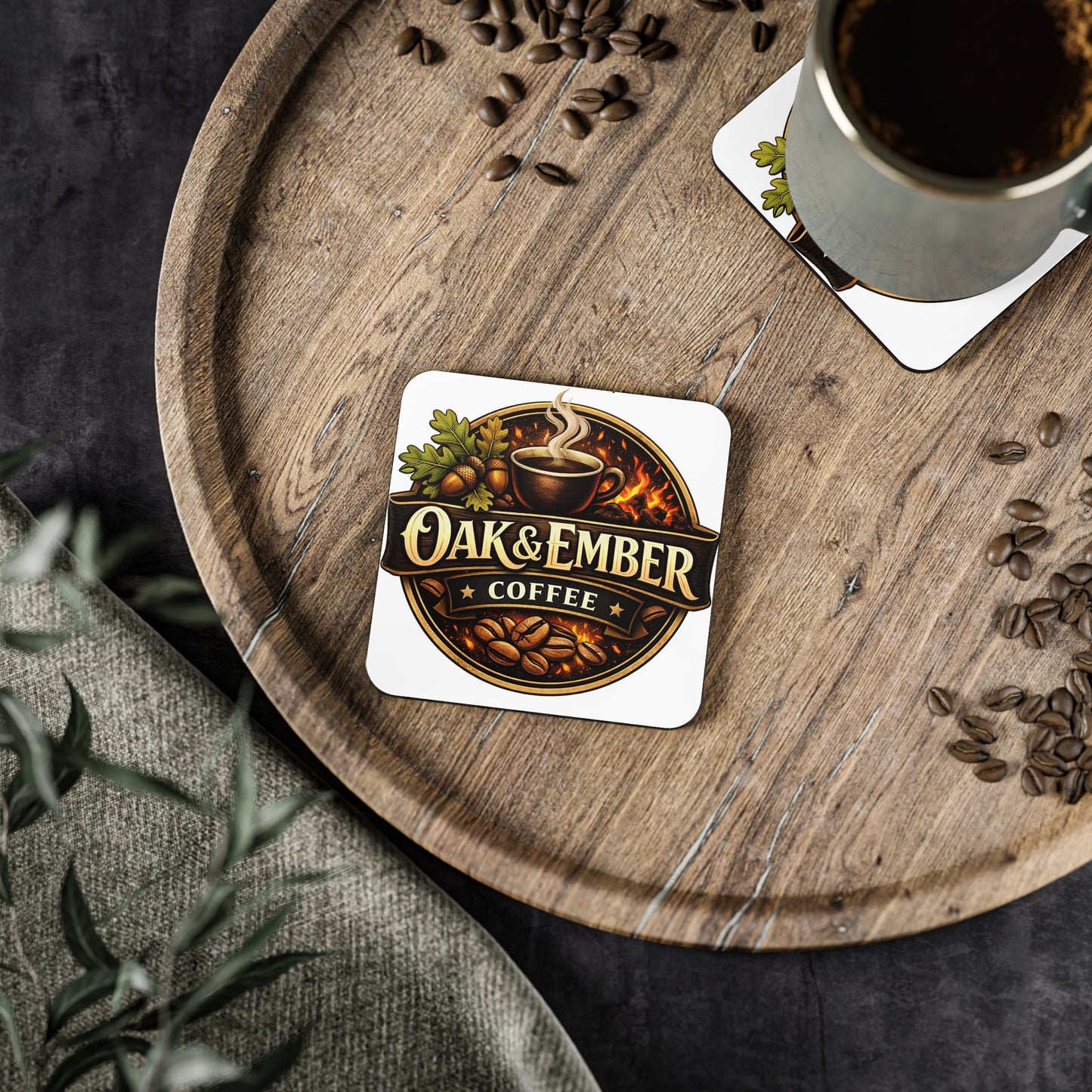 Coaster with 'Oak & Ember Coffee' logo on a wooden tray with coffee and coffee beans.